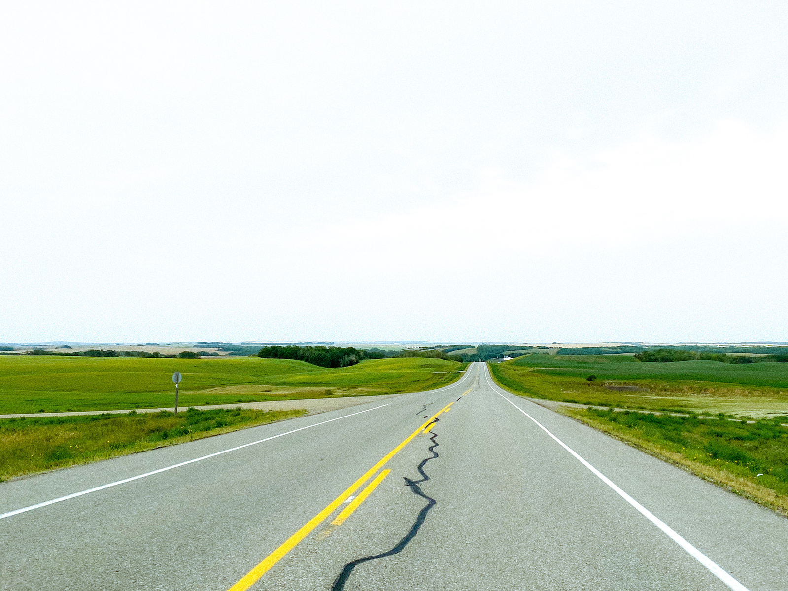 Two-lane prairie highway with a yellow centre line running to the horizon